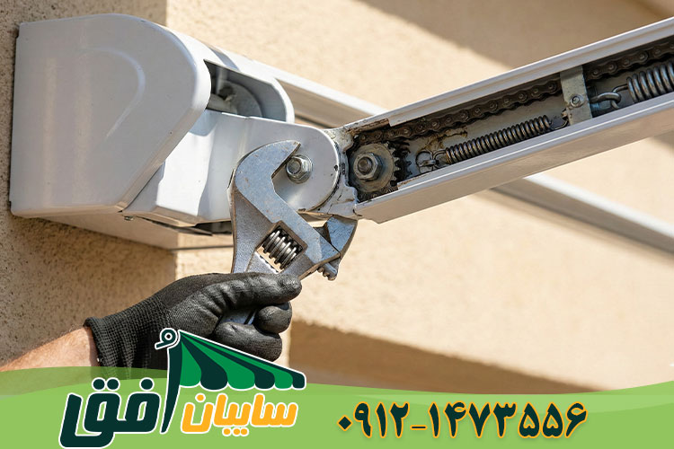 تعمیرکار در حال آچارکشی و تنظیم شیب بازوی مفصلی سایبان برقی جهت رفع افتادگی