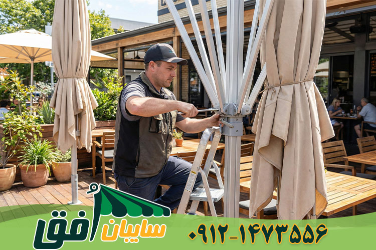 تکنسین در حال تعمیر هاب مرکزی و اتصالات شاخک‌های یک سایبان چتری بزرگ در فضای باز رستوران